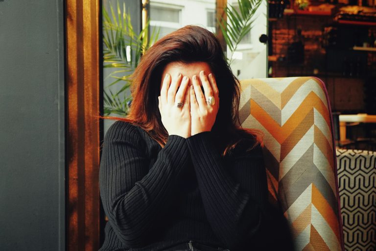 A woman holds her hands to her face in apparent embarrassment.