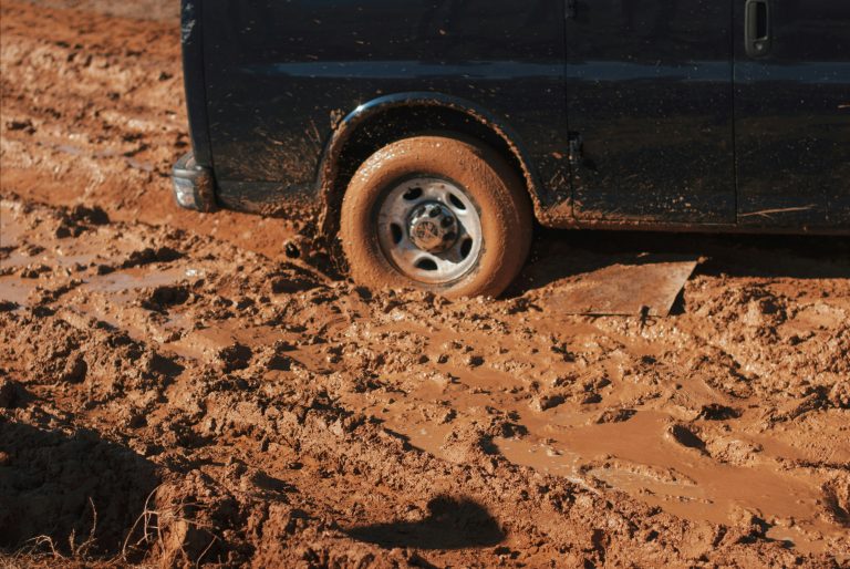 A truck's tire is stuck in the mud.