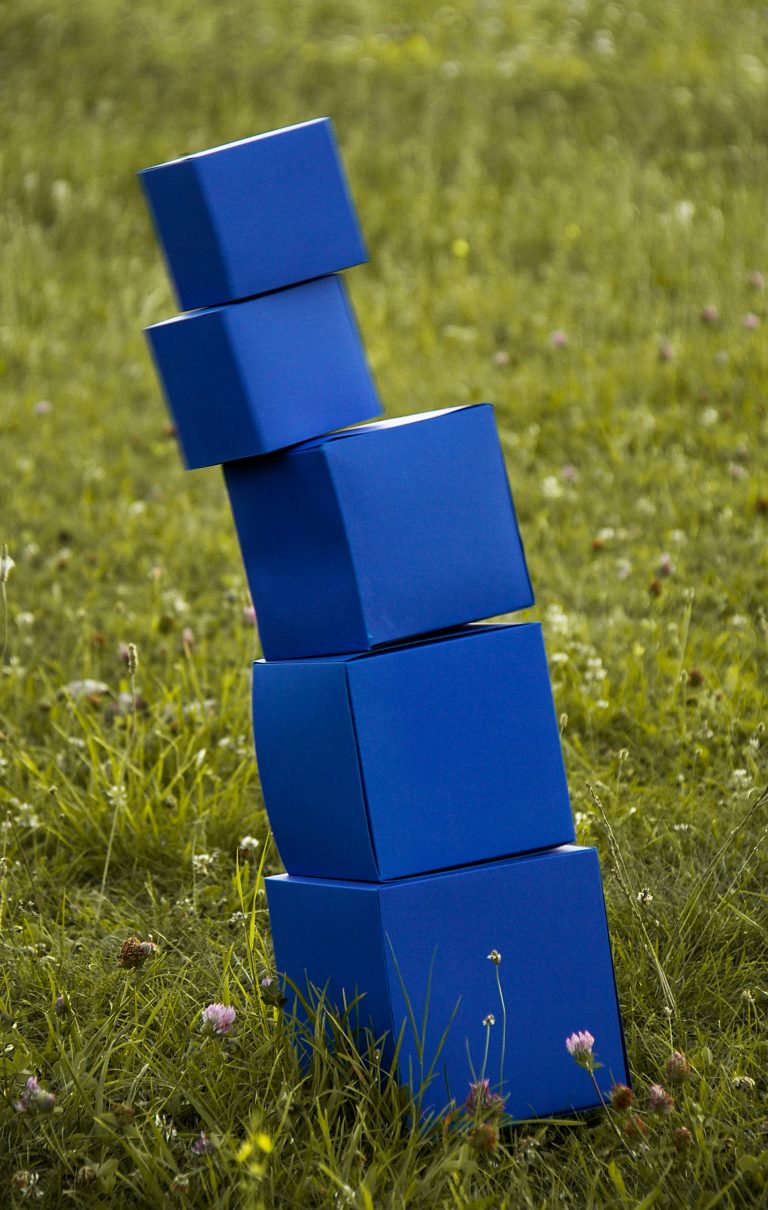 A stack of blue blocks tumbles in a field