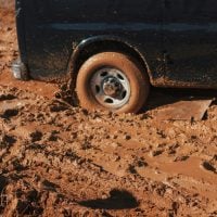 A truck's tire is stuck in the mud.