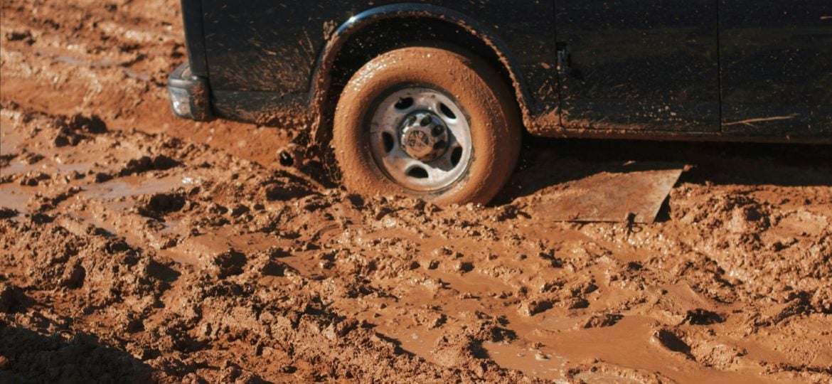 A truck's tire is stuck in the mud.