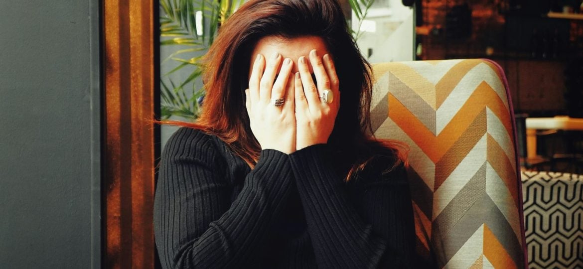 A woman holds her hands to her face in apparent embarrassment.