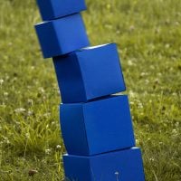 A stack of blue blocks tumbles in a field