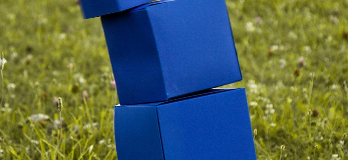 A stack of blue blocks tumbles in a field