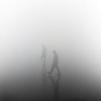 Two figures walk through a fog